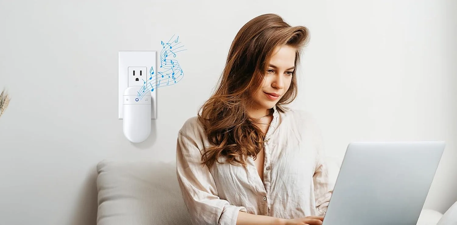 A SECRUI chime receiver ringing in an outlet beside a woman at a laptop